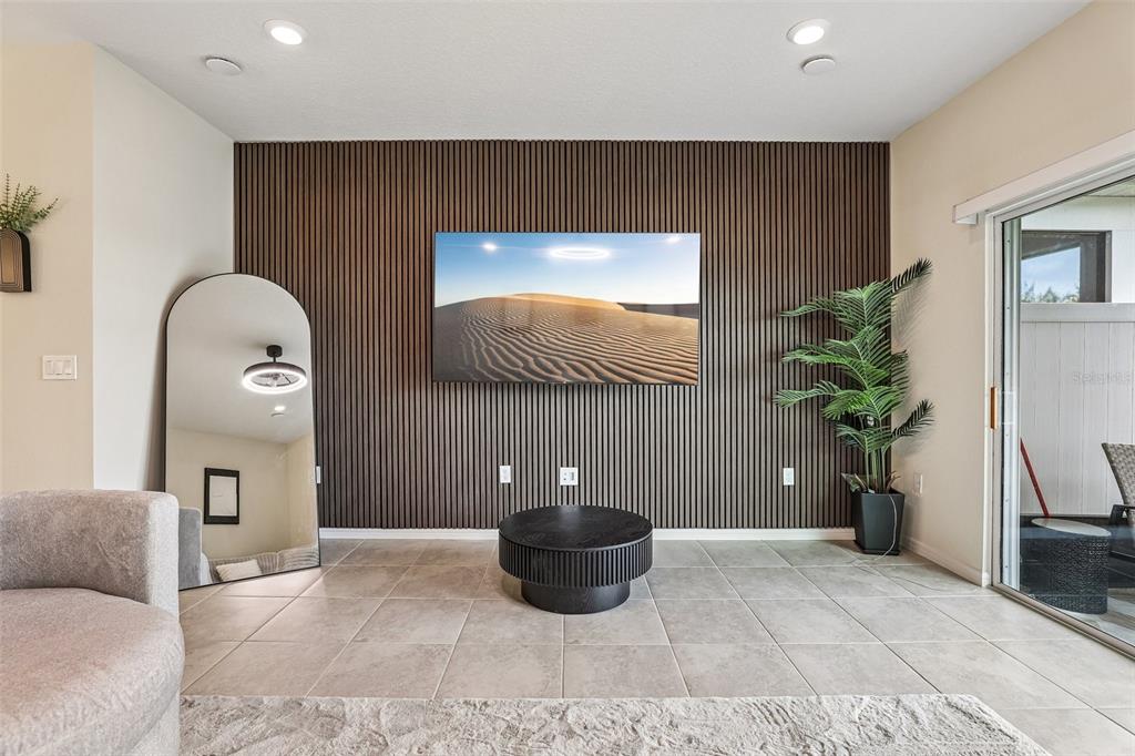 A living room features a slatted wood accent wall, a wall-mounted television, and tile flooring — 2570 WINSOME WAY, DAVENPORT, FL