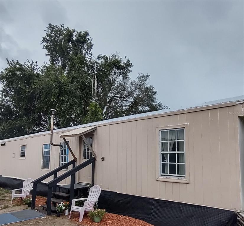 The exterior of a beige mobile home features a small wooden porch and a metal antenna — 17936 SE 95TH STREET ROAD, OCKLAWAHA, FL