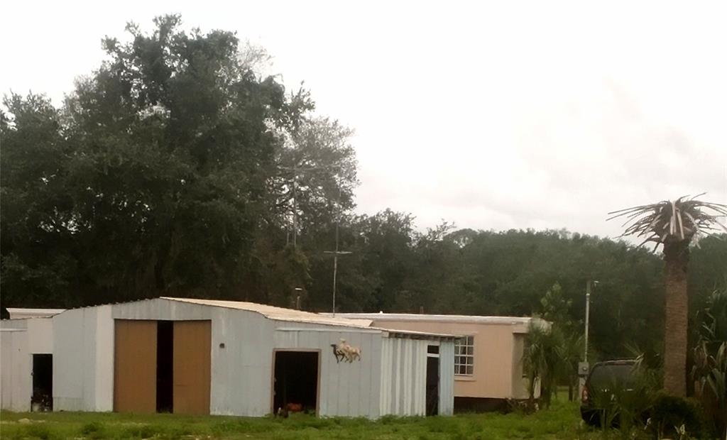A metal-sided outbuilding stands next to a mobile home near trees and a palm tree — 17936 SE 95TH STREET ROAD, OCKLAWAHA, FL