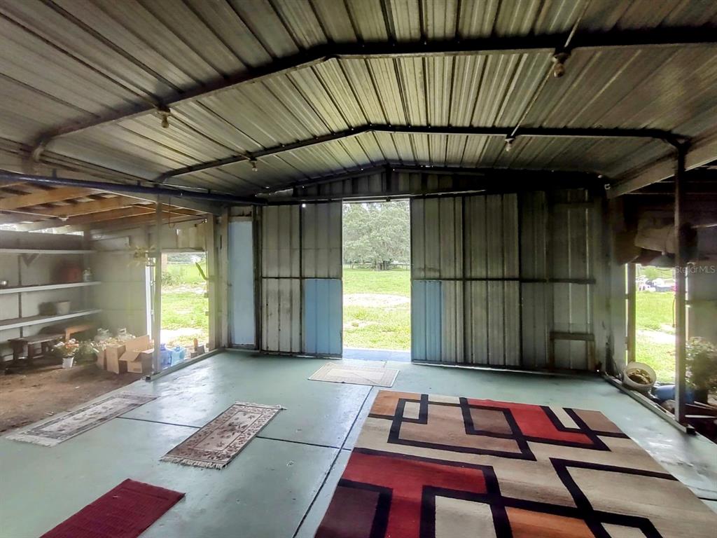 An open-air metal structure with a concrete floor, shelving, and sliding doors leading outside — 17936 SE 95TH STREET ROAD, OCKLAWAHA, FL