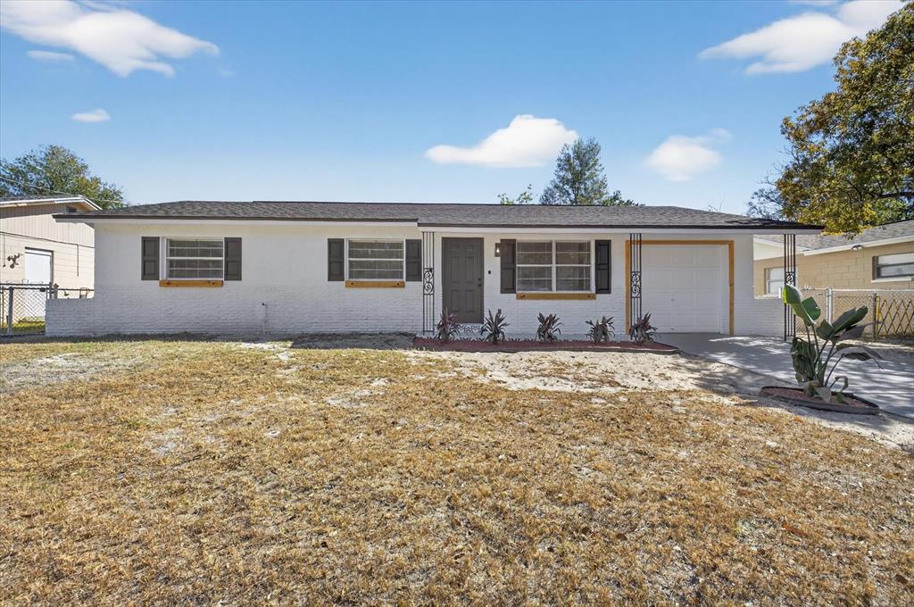 A single-story white house with a garage and a dry, patchy front lawn — 8309 TUPELO DRIVE, TAMPA, FL