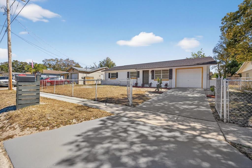 A white single-story house with a garage and a chain-link fence in the front yard — 8309 TUPELO DRIVE, TAMPA, FL