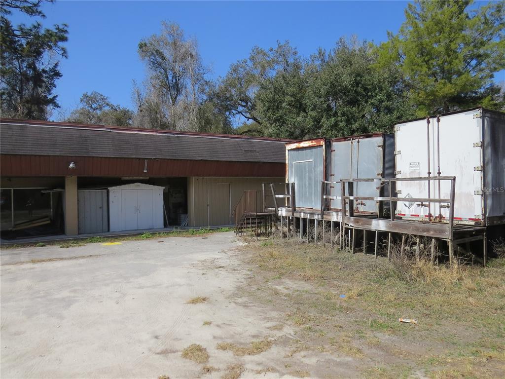 An exterior view shows a commercial building with attached storage containers on a raised platform — 28380 FORBES STREET, NOBLETON, FL
