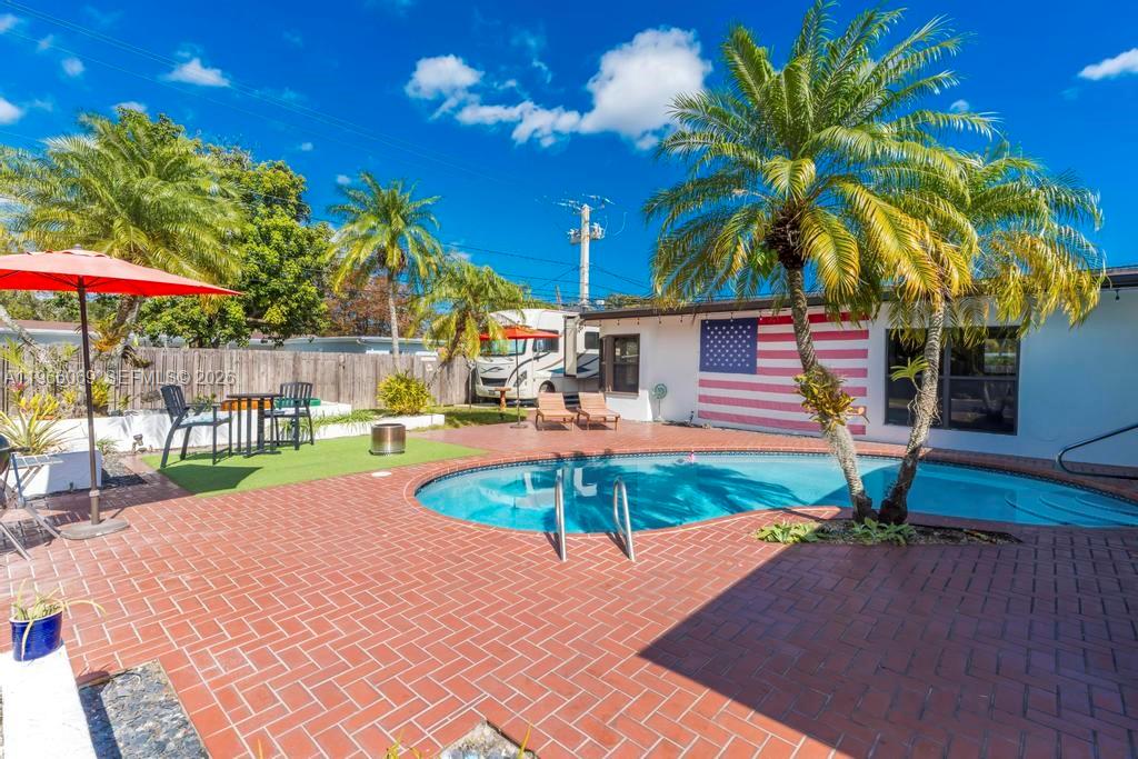 A backyard features a swimming pool, brick patio, palm trees, and an American flag wall mural — 5201 Jefferson St, Hollywood FL 33021, HOLLYWOOD, FL