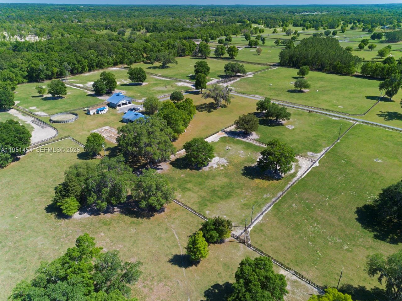 An aerial view shows a large rural property with fenced pastures, scattered trees, and buildings — 7787 NW 150TH AVE, Ocala FL 32668, OCALA, FL