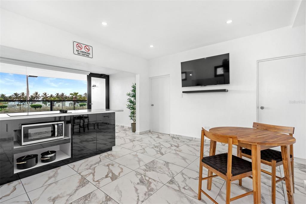 A modern kitchen and dining area with marble-look tile floors and a view of palm trees — 1035 CALLE MARGINAL VILLAMAR, CAROLINA, PR