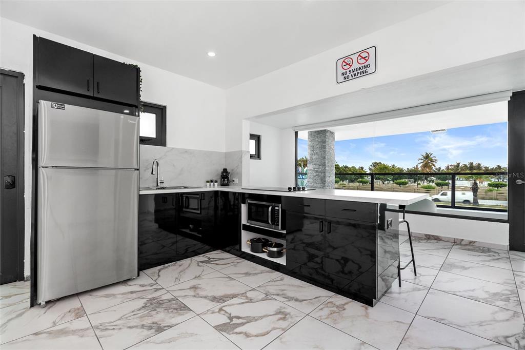 A modern kitchen features black cabinets, stainless steel appliances, marble-patterned tile floors, and a window view — 1035 CALLE MARGINAL VILLAMAR, CAROLINA, PR