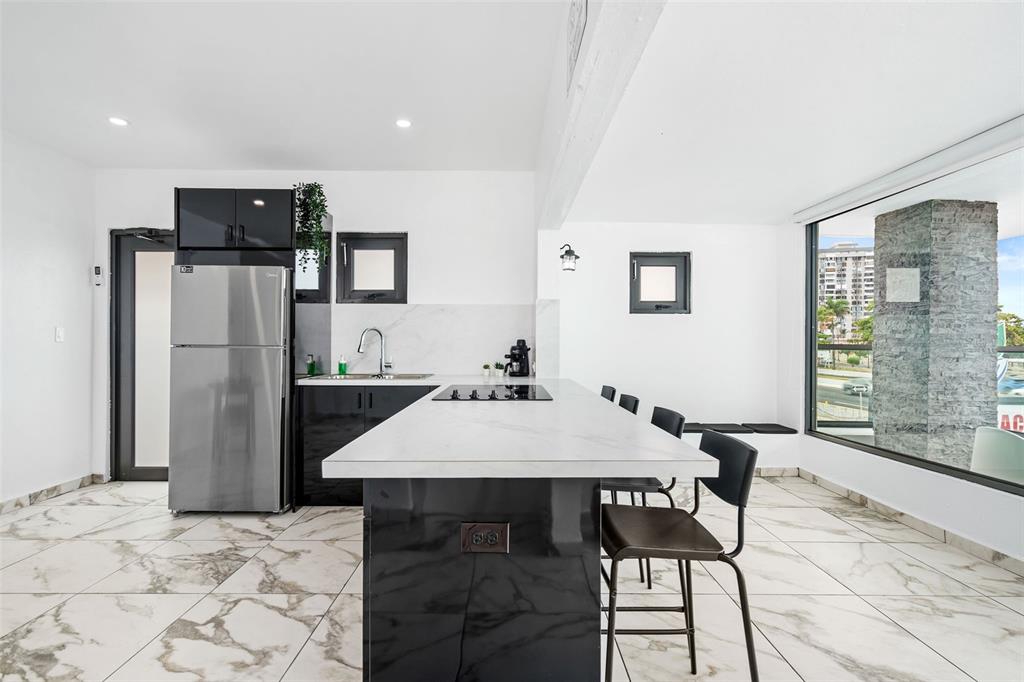 A modern kitchen features a white marble island, black cabinetry, and large floor-to-ceiling windows — 1035 CALLE MARGINAL VILLAMAR, CAROLINA, PR