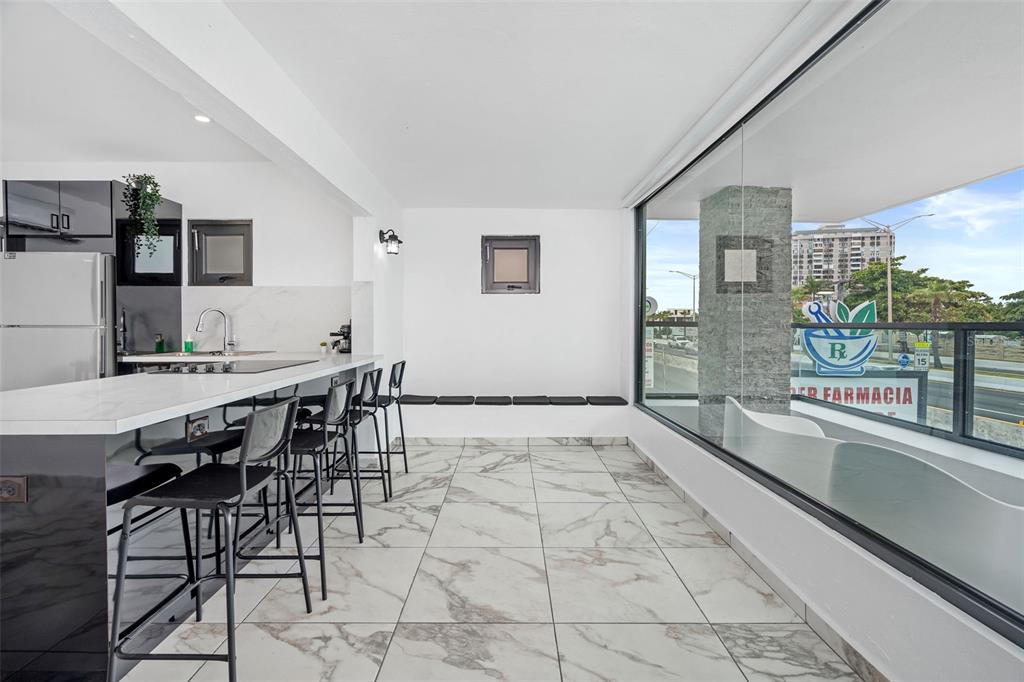A modern kitchen with a breakfast bar, marble-look tile floors, and large floor-to-ceiling windows — 1035 CALLE MARGINAL VILLAMAR, CAROLINA, PR