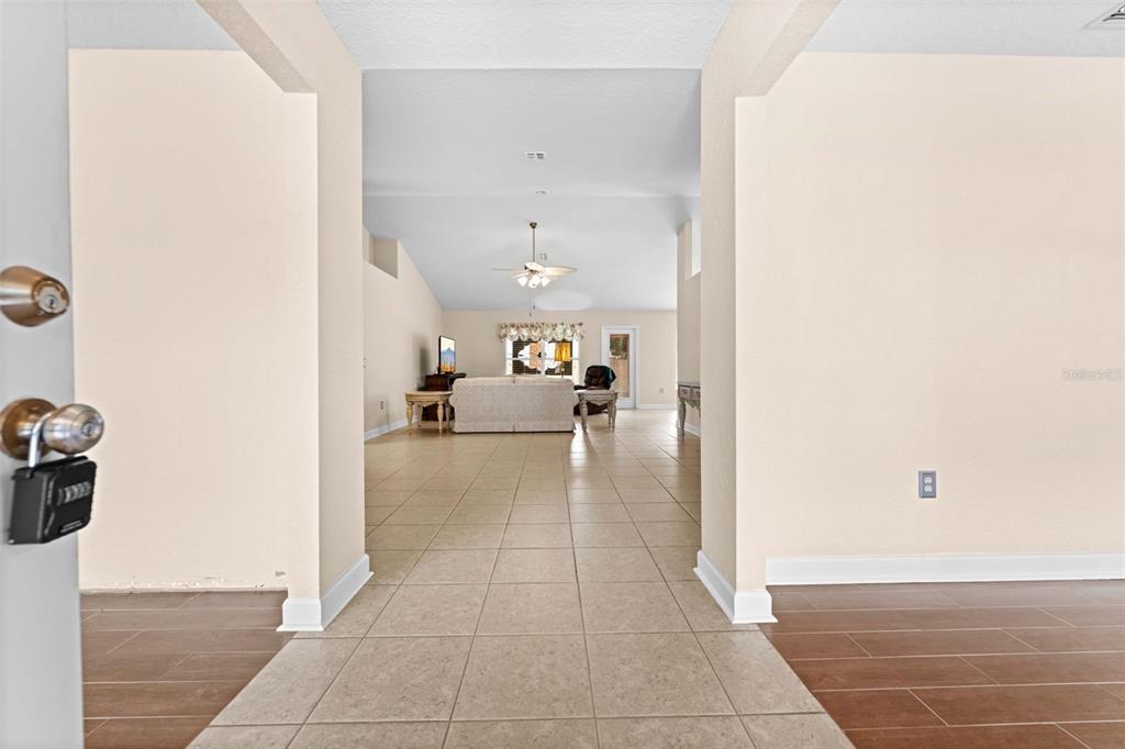 A view from an entryway looking into a living room with tiled floors — 8053 TIMBERLAKE AVENUE, SPRING HILL, FL
