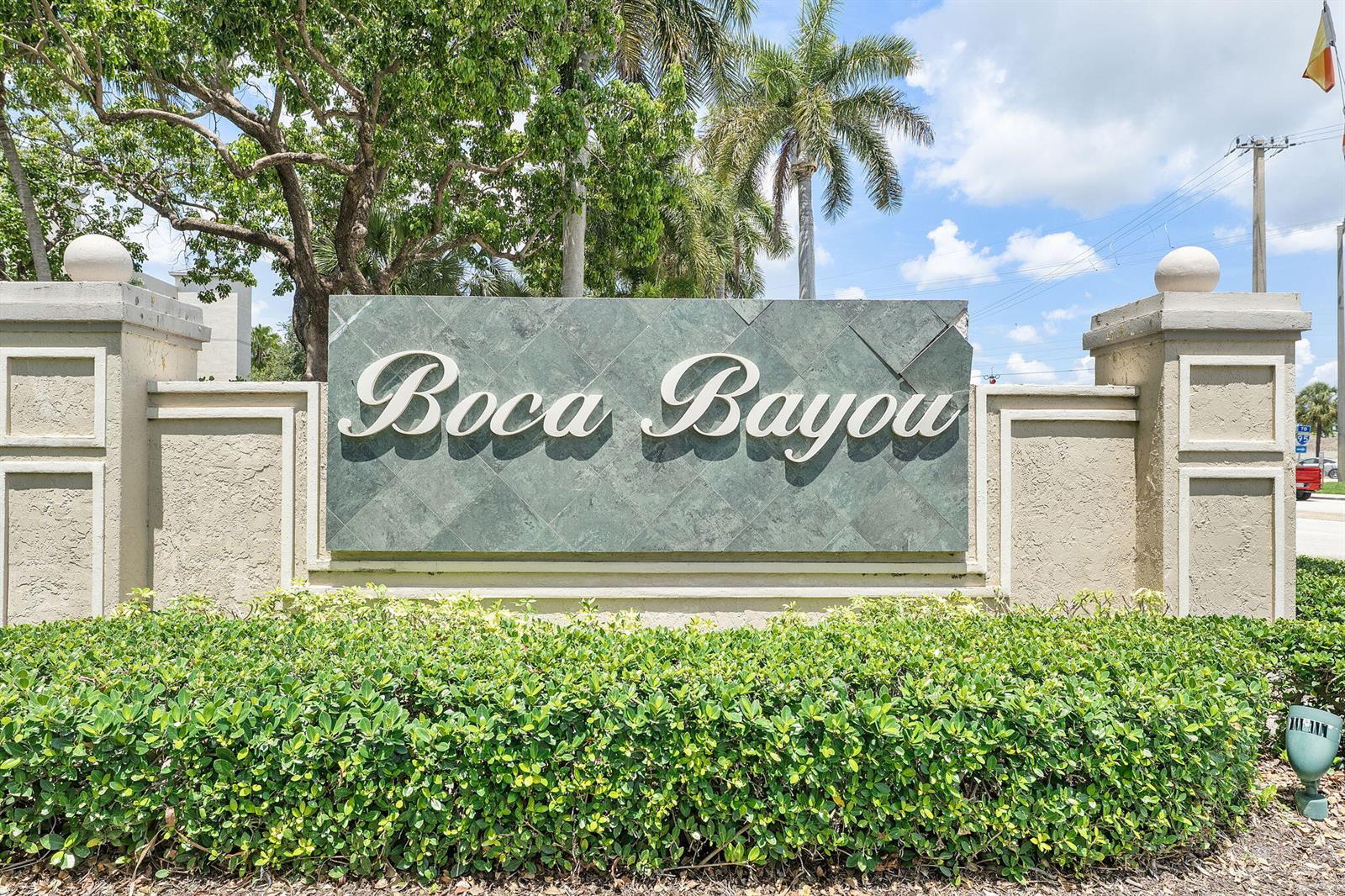 A green stone sign with the text Boca Bayou stands behind a manicured hedge — 20 Royal Palm Way # 2060, Boca Raton FL 33432, BOCA RATON, FL