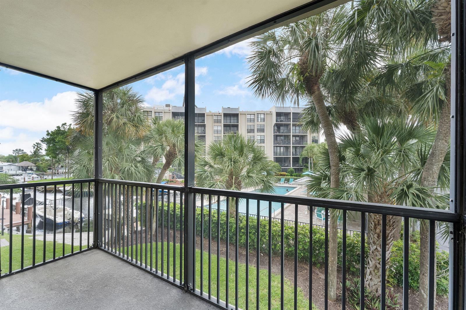 A screened-in balcony overlooks a swimming pool, palm trees, and a boat dock — 20 Royal Palm Way # 2060, Boca Raton FL 33432, BOCA RATON, FL