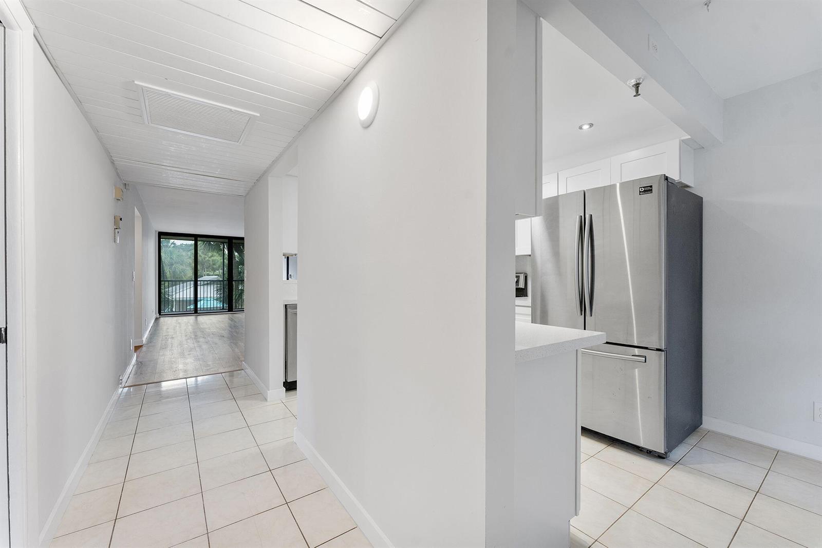 A tiled hallway leads to a living area with a balcony, adjacent to a kitchen — 20 Royal Palm Way # 2060, Boca Raton FL 33432, BOCA RATON, FL