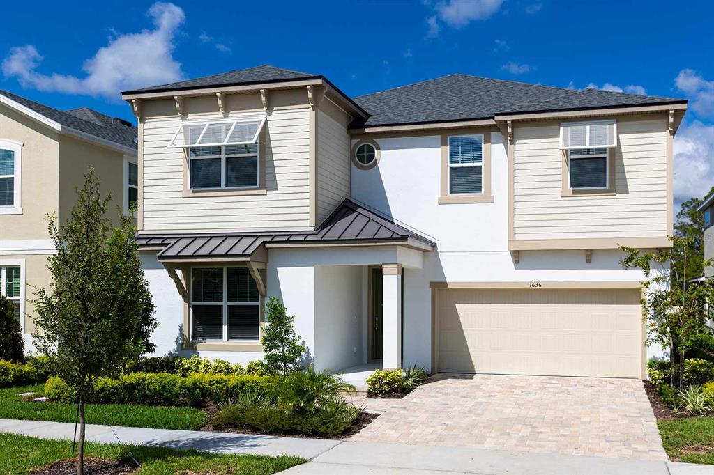 A two-story suburban house with a white stucco facade, tan siding, and a two-car garage — 1636 NASSAU POINT TRAIL, KISSIMMEE, FL