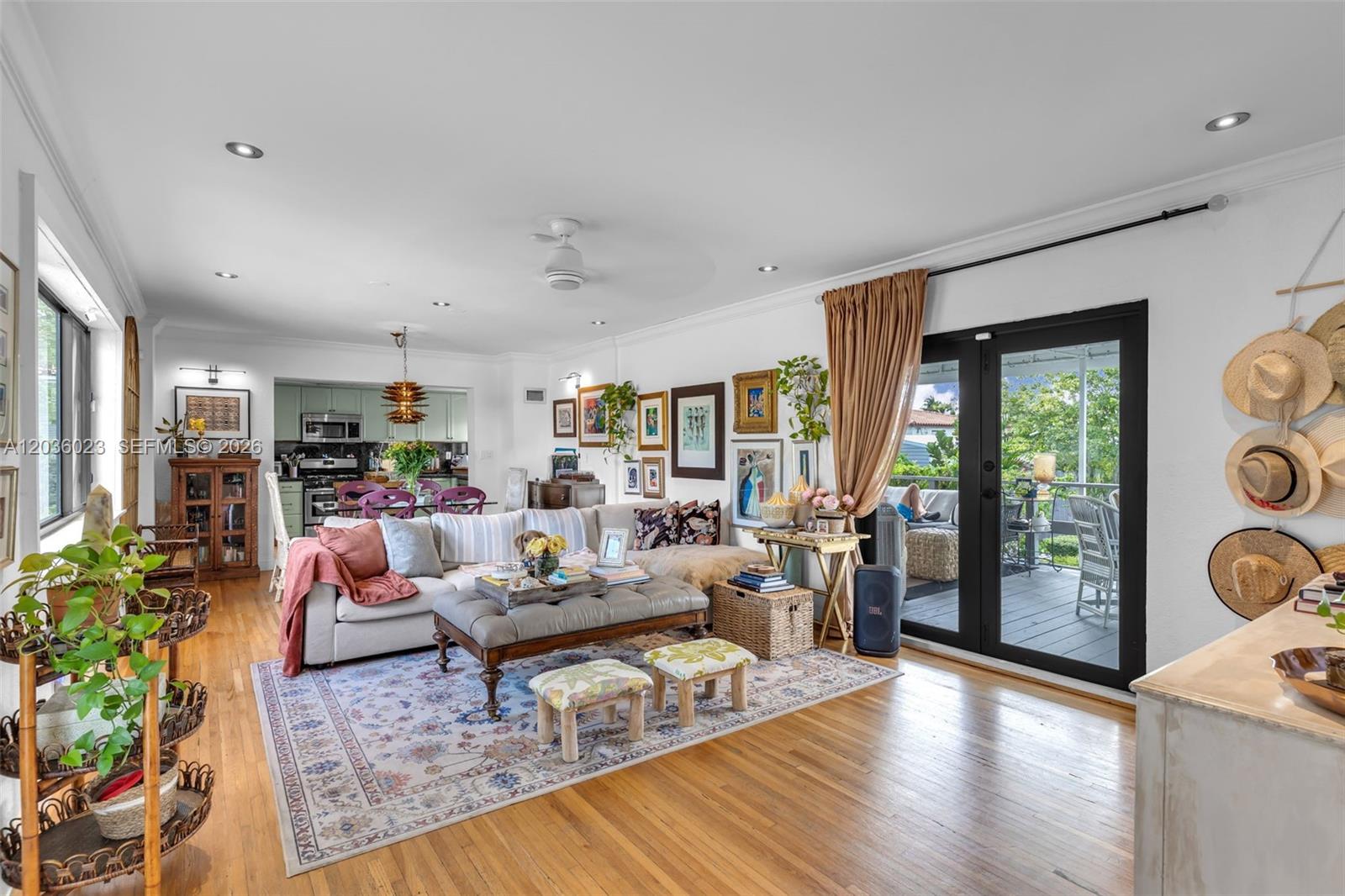 A living room with hardwood floors, a sectional sofa, and glass doors leading to a deck — 8281 SW 27th Ln, Miami FL 33155, MIAMI, FL