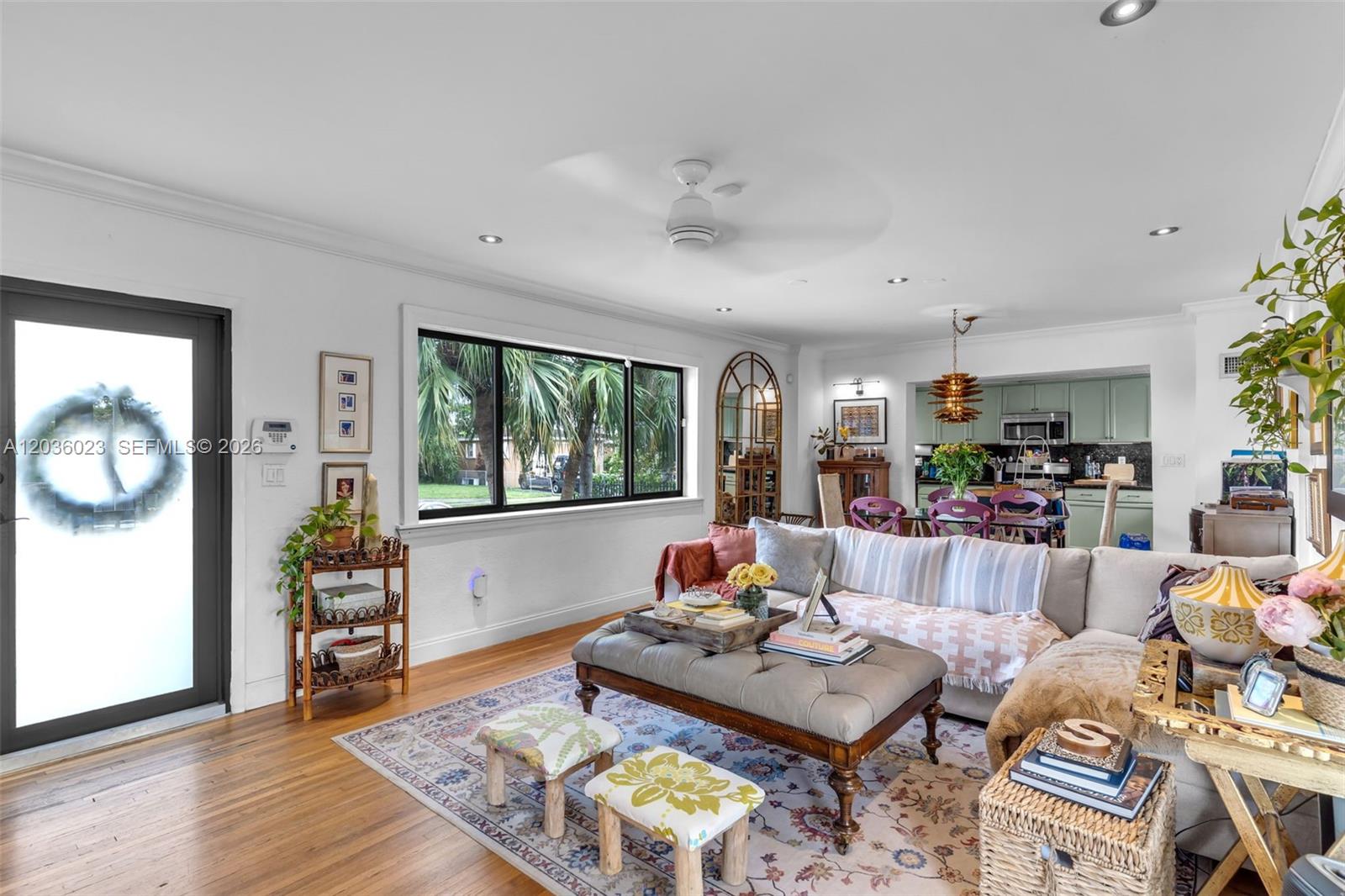 A living room with hardwood floors, a tufted ottoman, and an open kitchen in back — 8281 SW 27th Ln, Miami FL 33155, MIAMI, FL