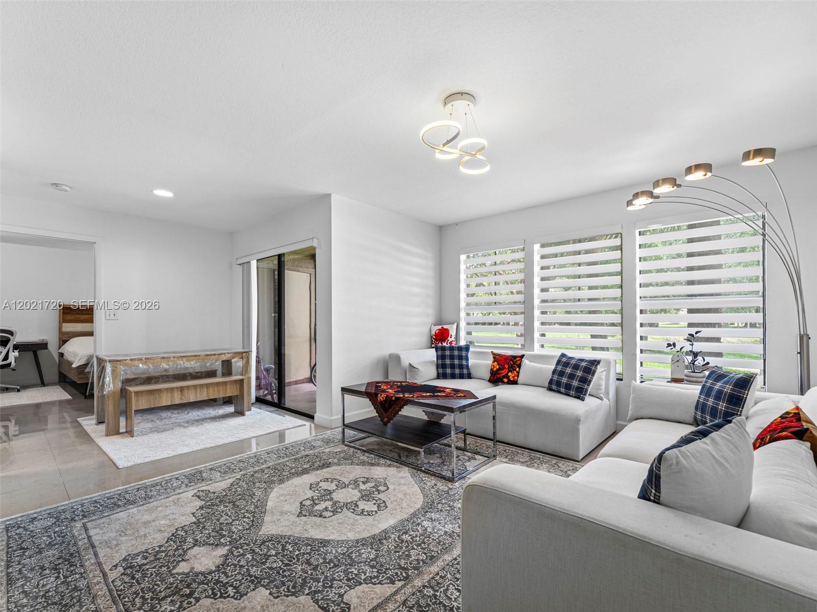 A living room features a sectional sofa, a dining area, and large windows with blinds — MIAMI, FL