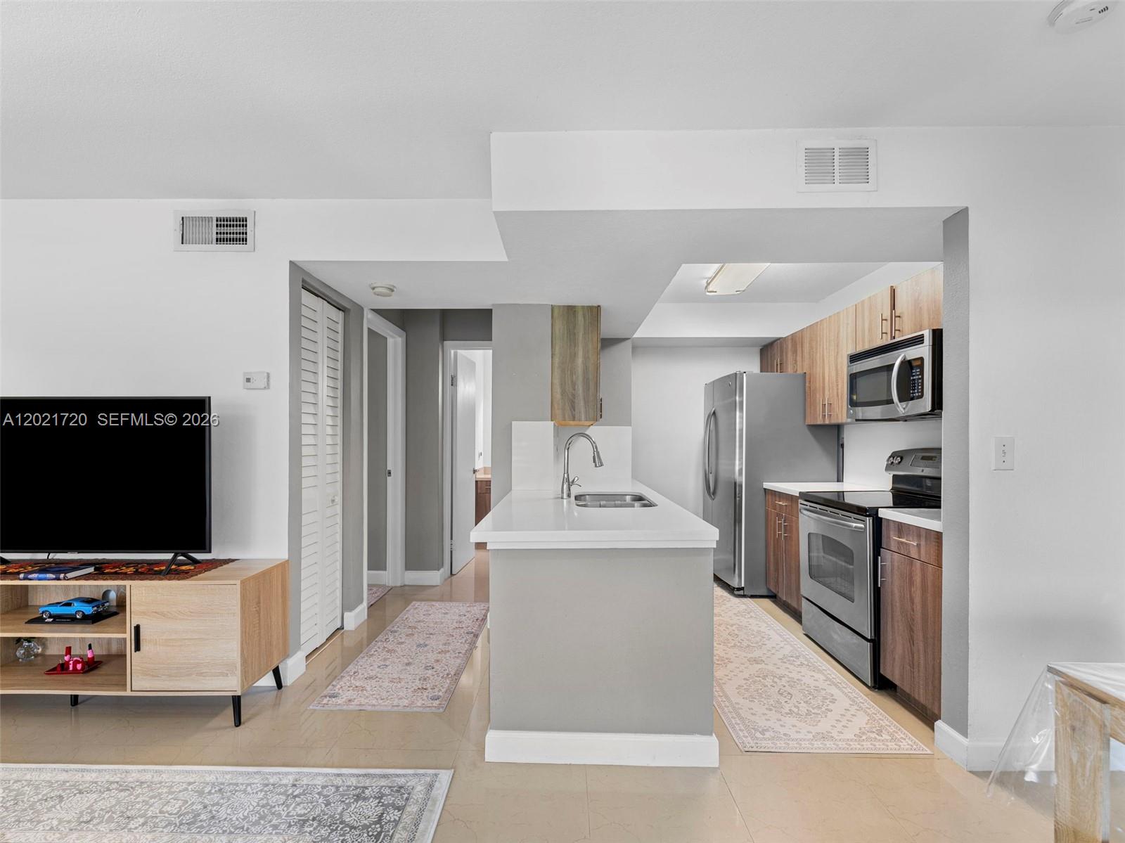 A kitchen with wood cabinets, stainless steel appliances, and a white island countertop — MIAMI, FL