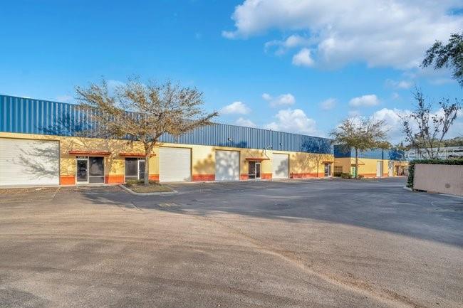 A long, single-story industrial warehouse building with multiple roll-up doors and a paved parking lot — 201 REECE WAY UNIT 1425, CASSELBERRY, FL