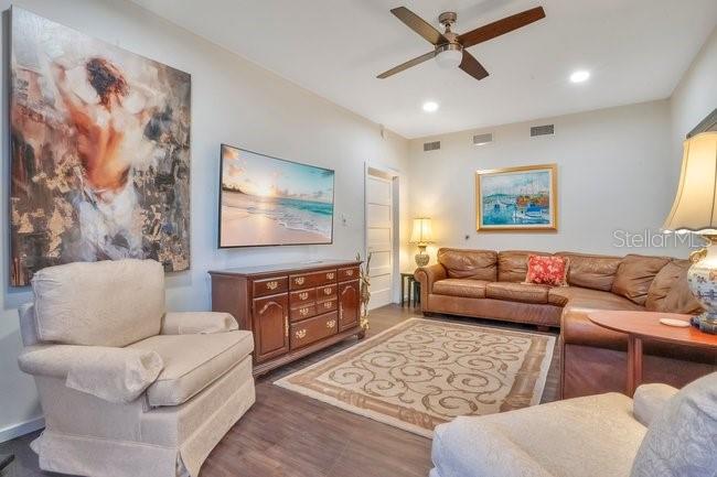 A living room features a beige armchair, a brown leather sofa, and a wooden dresser — 201 REECE WAY UNIT 1425, CASSELBERRY, FL