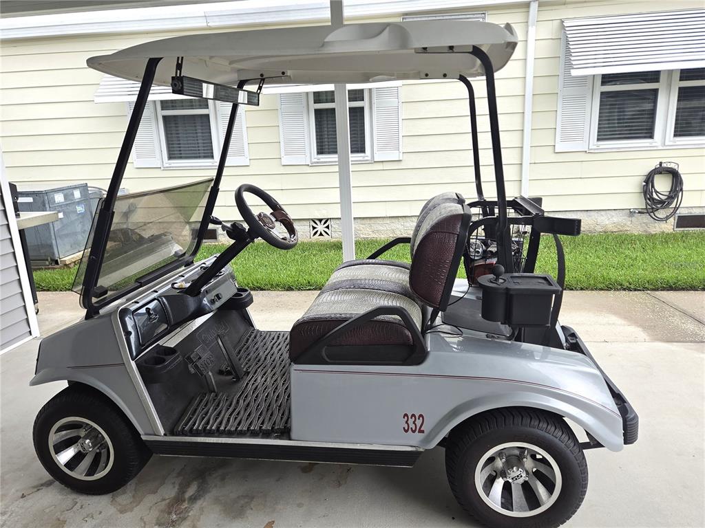 A silver golf cart with custom seats and wheels is parked on a concrete driveway — 332 VICTORIA DRIVE, HAINES CITY, FL