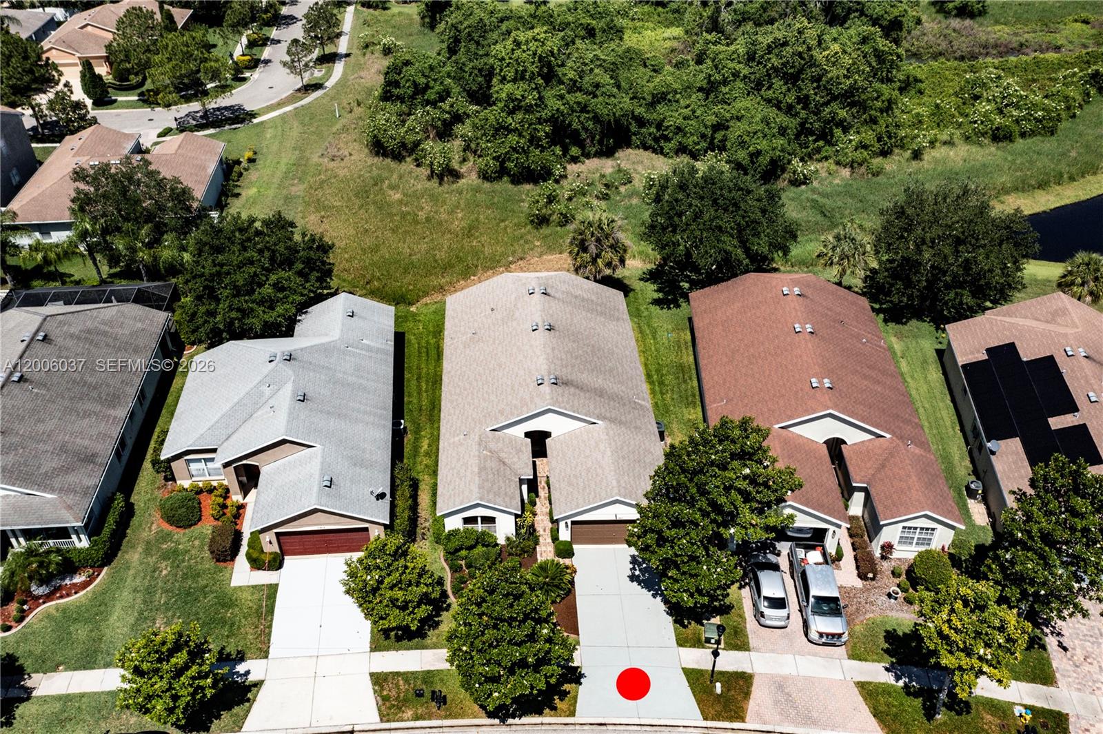 An aerial view shows three suburban houses with driveways and lawns near a wooded area — 11413 MOUNTAIN BAY DR, Riverview FL 33569, RIVERVIEW, FL