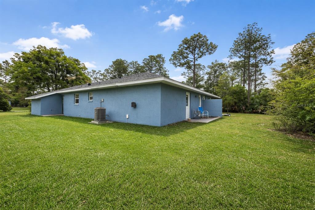 A blue stucco house exterior with a grassy yard, an air conditioning unit, and trees — 9 WHEELER PLACE UNIT A, B, PALM COAST, FL