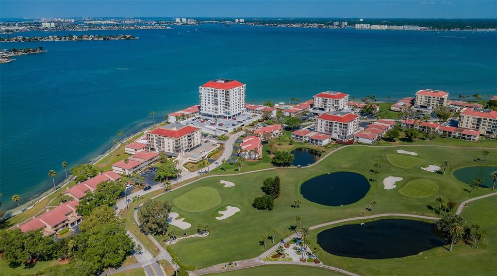 An aerial view shows a waterfront residential complex with a golf course and multiple pools — 6051 SUN BOULEVARD UNIT 305, ST PETERSBURG, FL