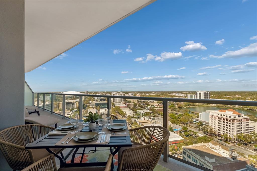 A high-rise balcony features a dining set and lounge chair overlooking a city skyline — 400 CENTRAL AVENUE UNIT 2102, ST PETERSBURG, FL