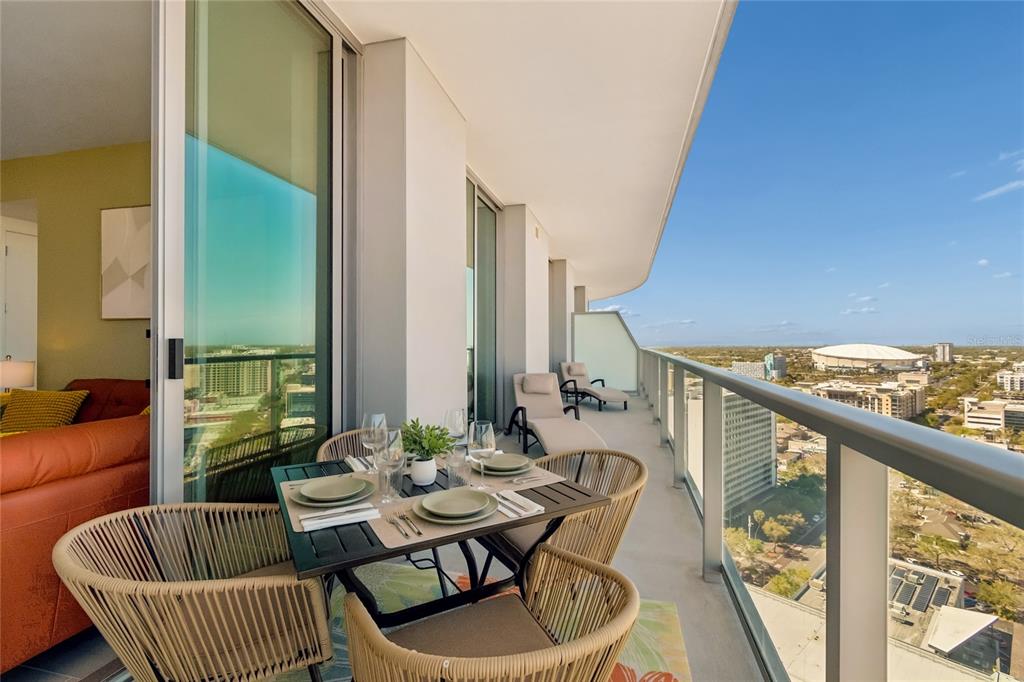 A balcony with a dining set and lounge chairs overlooks a city and stadium — 400 CENTRAL AVENUE UNIT 2102, ST PETERSBURG, FL