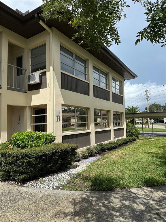 A two-story apartment building exterior features tan stucco walls, dark brown trim, and large windows — 4826 MARINE PARKWAY UNIT 202, NEW PORT RICHEY, FL