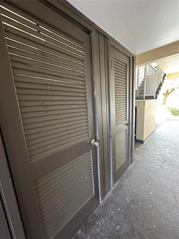 Two brown louvered doors are set into a wall on an outdoor walkway — 4826 MARINE PARKWAY UNIT 202, NEW PORT RICHEY, FL