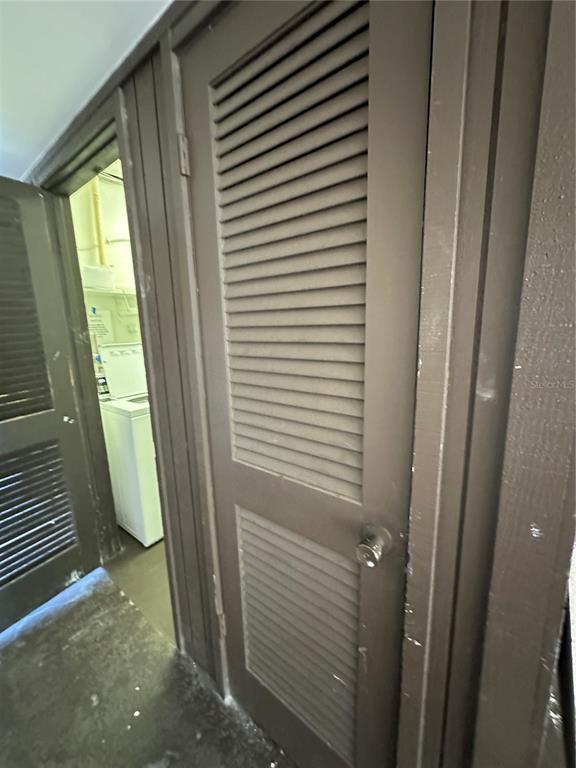 A view of a laundry area with a white washing machine behind brown louvered doors — 4826 MARINE PARKWAY UNIT 202, NEW PORT RICHEY, FL
