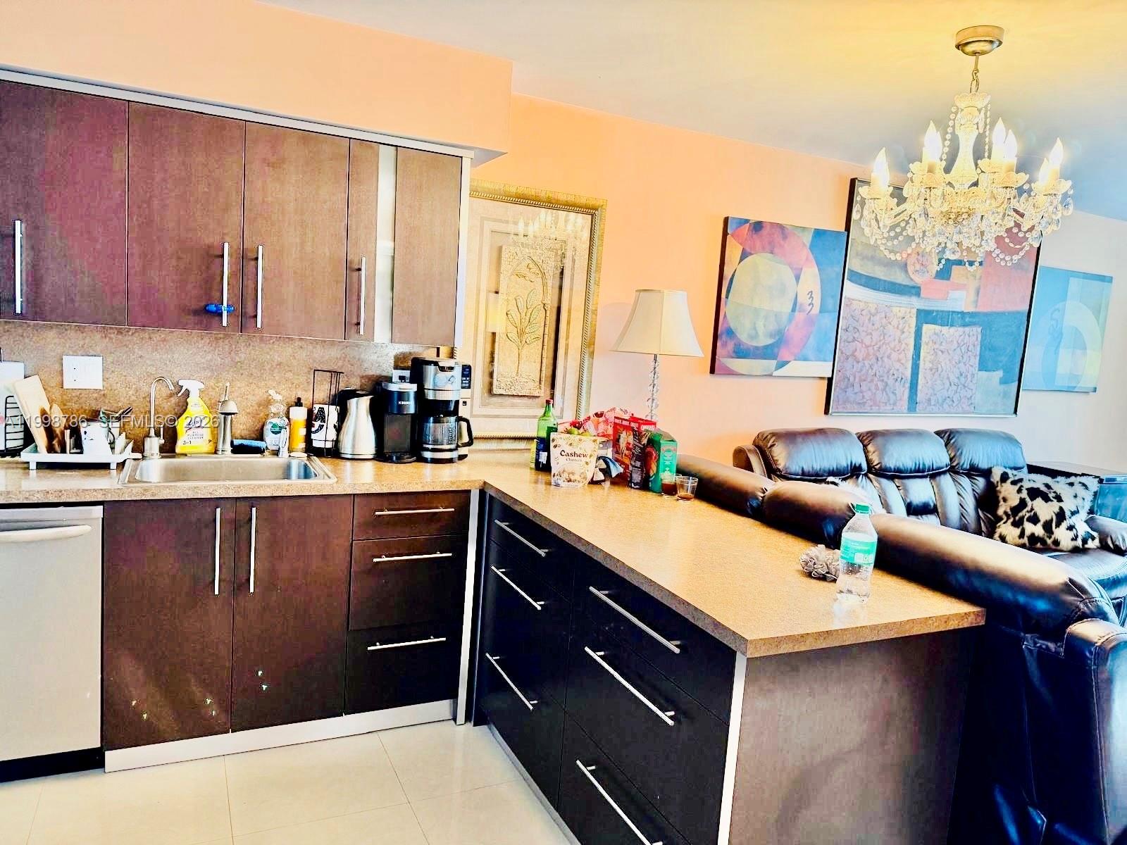 A kitchen with dark wood cabinets and a breakfast bar overlooks a living area — 1150 NE 191st St # 38, Miami FL 33179, MIAMI, FL