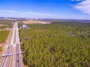An aerial view shows a multi-lane highway running alongside a large, undeveloped wooded lot — 0 INTERNATIONAL DRIVE, ORLANDO, FL