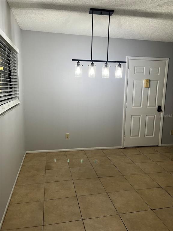 A dining area features light gray walls, tan tile flooring, and a modern four-light pendant — 3300 FOX CHASE CIRCLE N UNIT 226, PALM HARBOR, FL