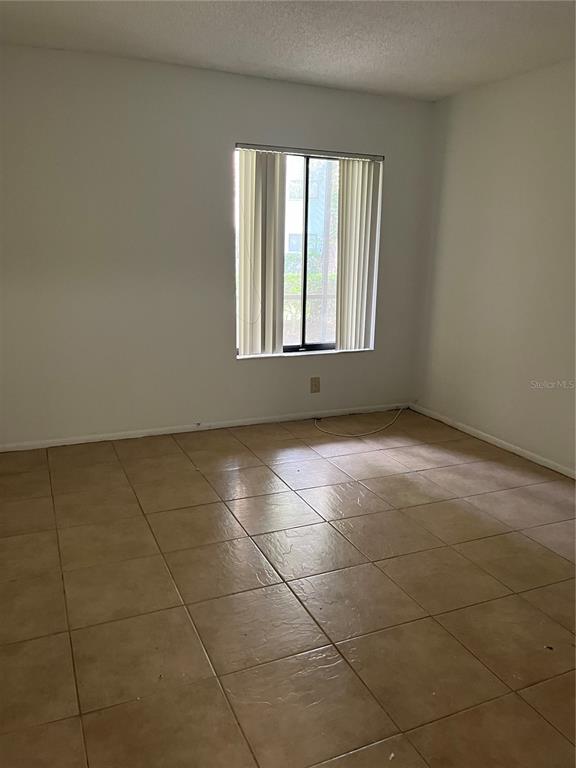 An empty room features light-colored walls, a single window with vertical blinds, and tiled flooring — 3300 FOX CHASE CIRCLE N UNIT 226, PALM HARBOR, FL