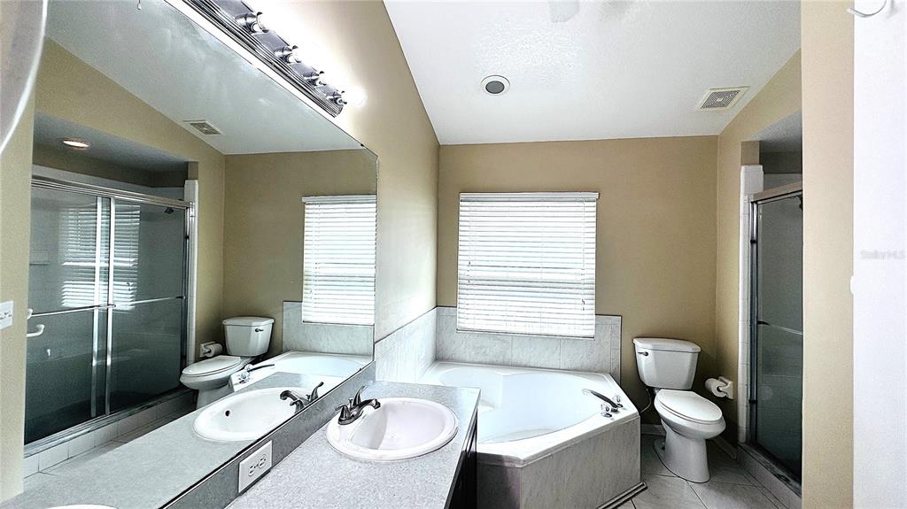 A bathroom features a dual vanity, a corner soaking tub, and a separate glass shower — 10903 RUSHWOOD WAY, CLERMONT, FL