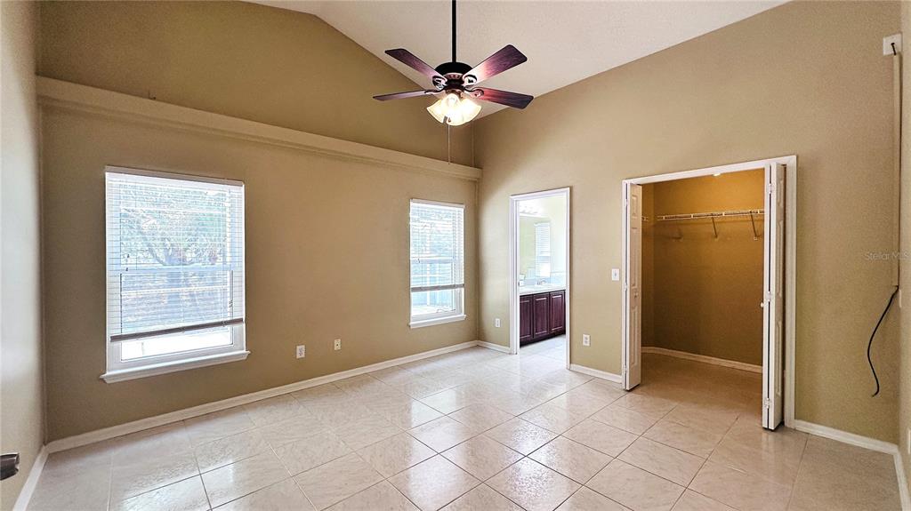 A bedroom with tiled floors, a vaulted ceiling, a ceiling fan, and an attached closet — 10903 RUSHWOOD WAY, CLERMONT, FL