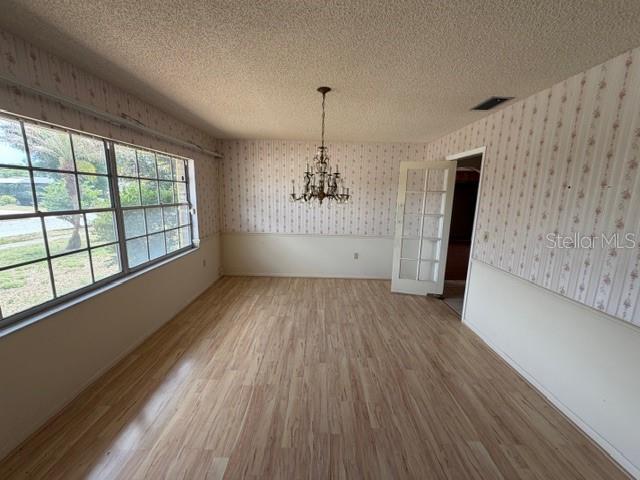 A dining room with light wood-look flooring, floral wallpaper, a chandelier, and large windows — 1105 GAUSE AVENUE, BARTOW, FL