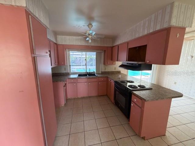 A kitchen features pink cabinets, tile flooring, a ceiling fan, and a window overlooking a pool — 1105 GAUSE AVENUE, BARTOW, FL