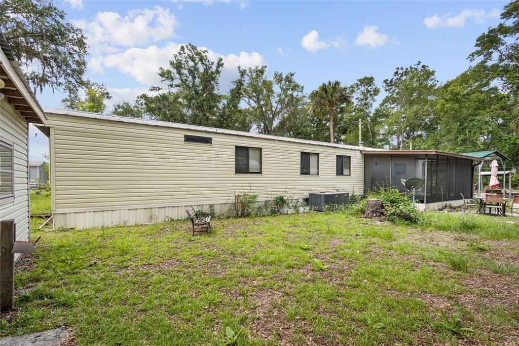 The exterior of a beige mobile home with a screened-in porch and a grassy yard — 9949 NW 55TH STREET, CHIEFLAND, FL