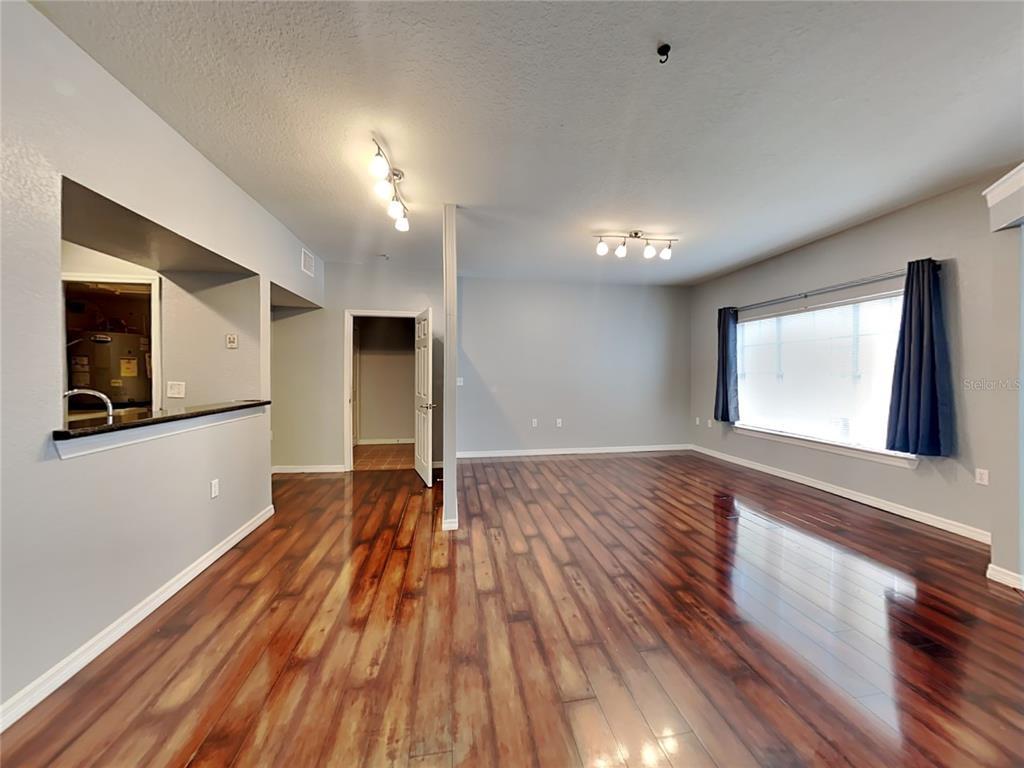 An empty room features dark wood-look flooring, light gray walls, and two ceiling light fixtures — 2328 MIDTOWN TERRACE UNIT 1024, ORLANDO, FL