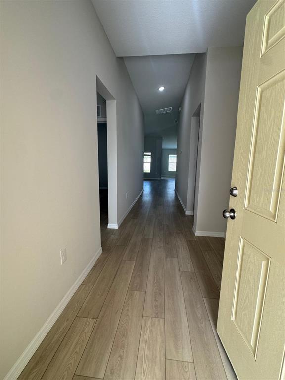 An interior view of a hallway with light wood-look flooring and a light-colored door — 1049 FORESHORE LANE, HAINES CITY, FL