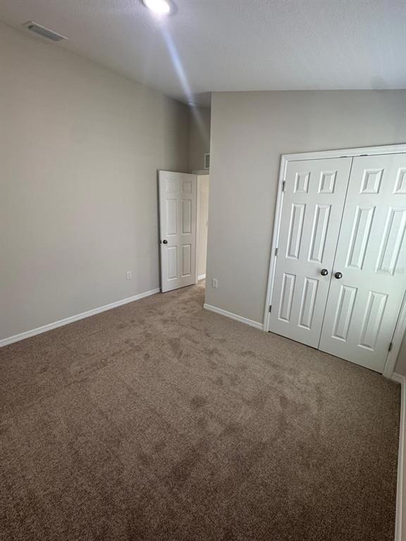 A bedroom with beige walls, brown carpeting, a closet with double doors, and an open doorway — 1049 FORESHORE LANE, HAINES CITY, FL