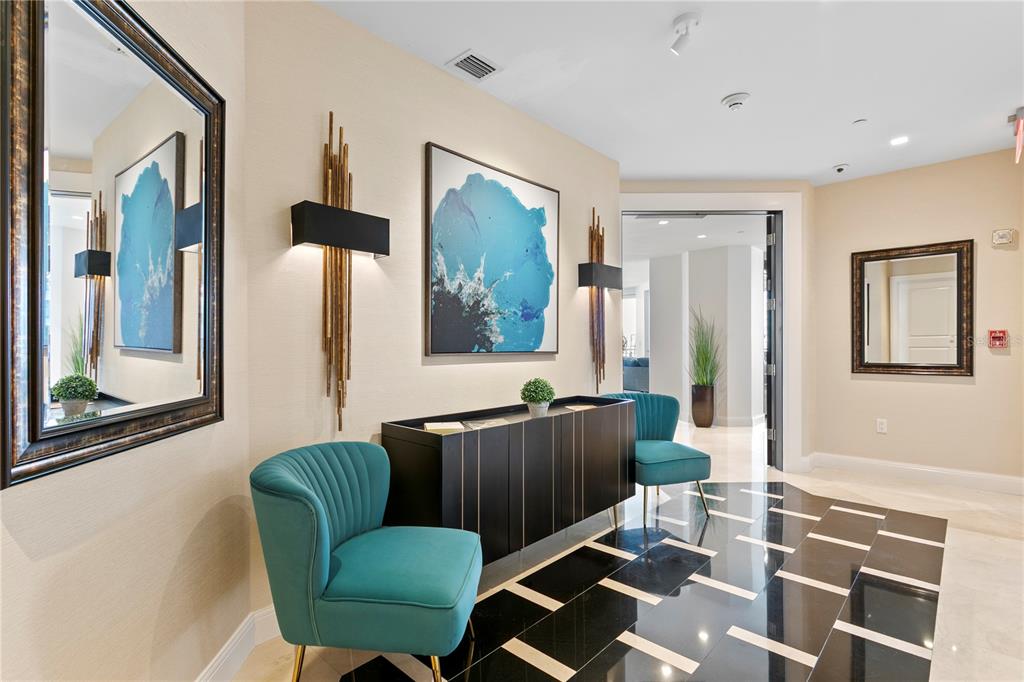 A modern entryway features teal armchairs, a black console table, wall art, and tiled flooring — 450 KNIGHTS RUN AVENUE UNIT 1801, TAMPA, FL