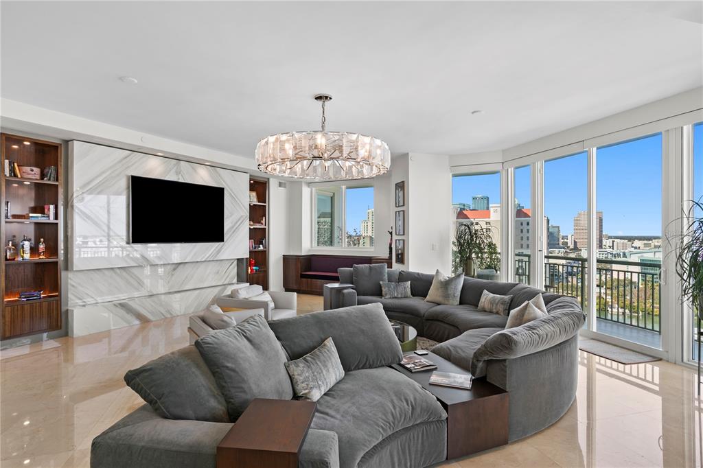 A modern living room features a large gray sectional, marble accent wall, and floor-to-ceiling windows — 450 KNIGHTS RUN AVENUE UNIT 1801, TAMPA, FL