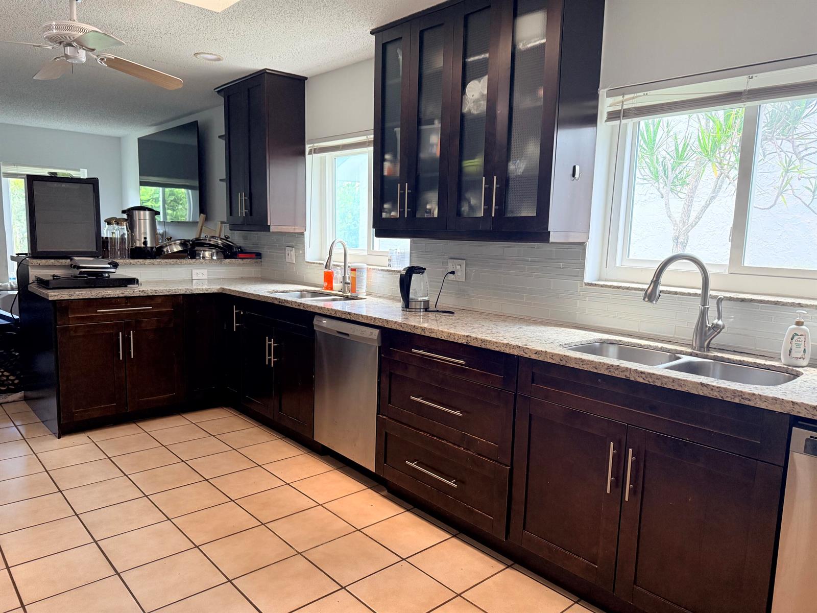 A kitchen features dark wood cabinets, granite countertops, tile flooring, and two stainless steel sinks — 7797 San Marcos Place, Boca Raton FL 33433, BOCA RATON, FL