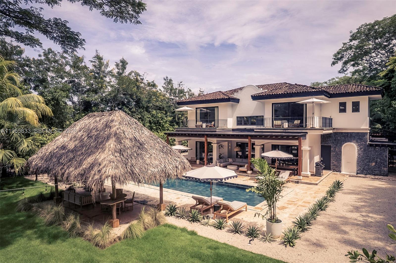A two-story villa with a thatched-roof palapa, swimming pool, and stone patio area — 90 Reserva De Golf, IA 50319, IA