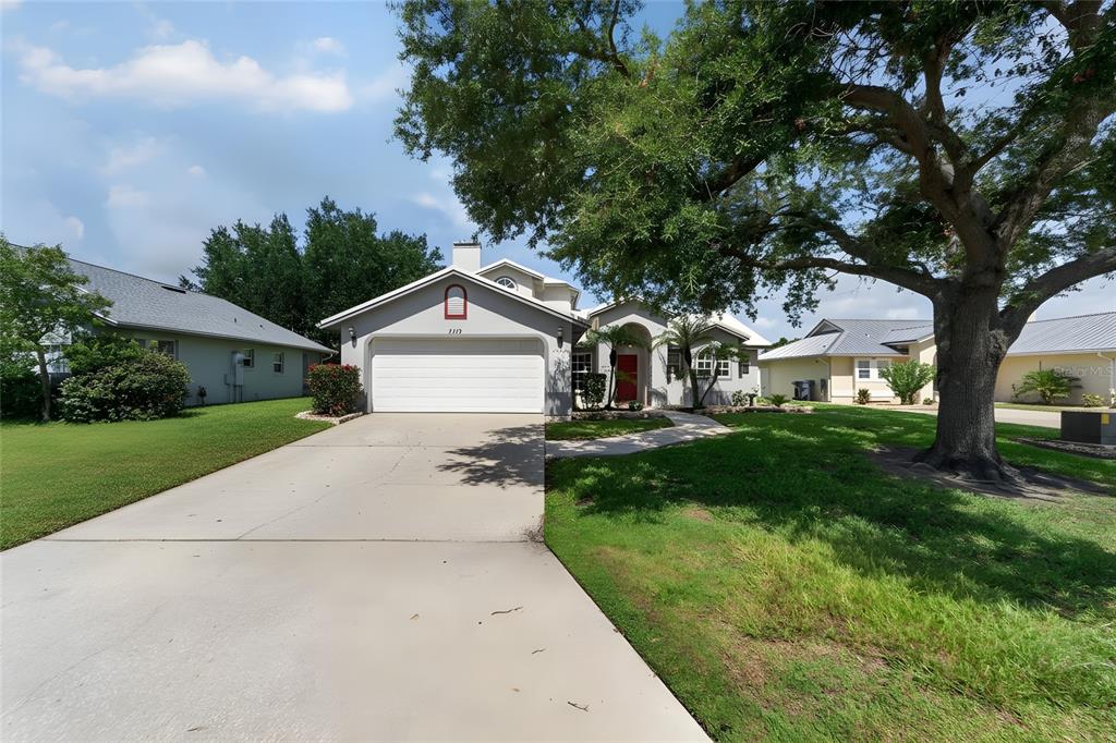 A single-story house with a white garage, gray siding, and a large tree in front — 5309 ST LUCIA DRIVE, LAKELAND, FL